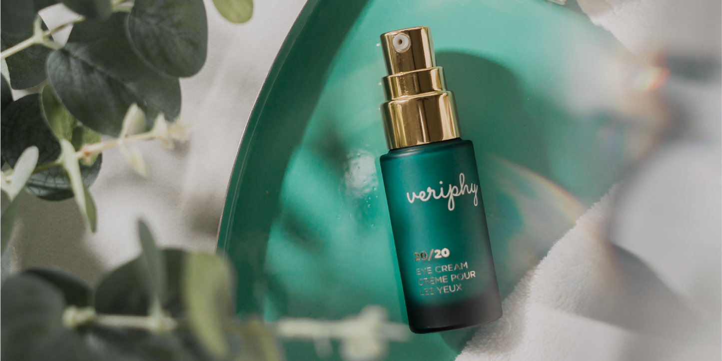 Veriphy Skincare 20/20 Eye Cream green glass bottle with gold cap floating in front of green botanical leaves
